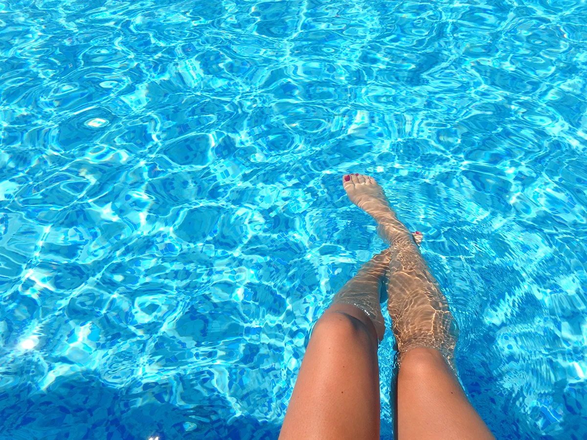Gambe di ragazza a mollo nell'acqua della piscina